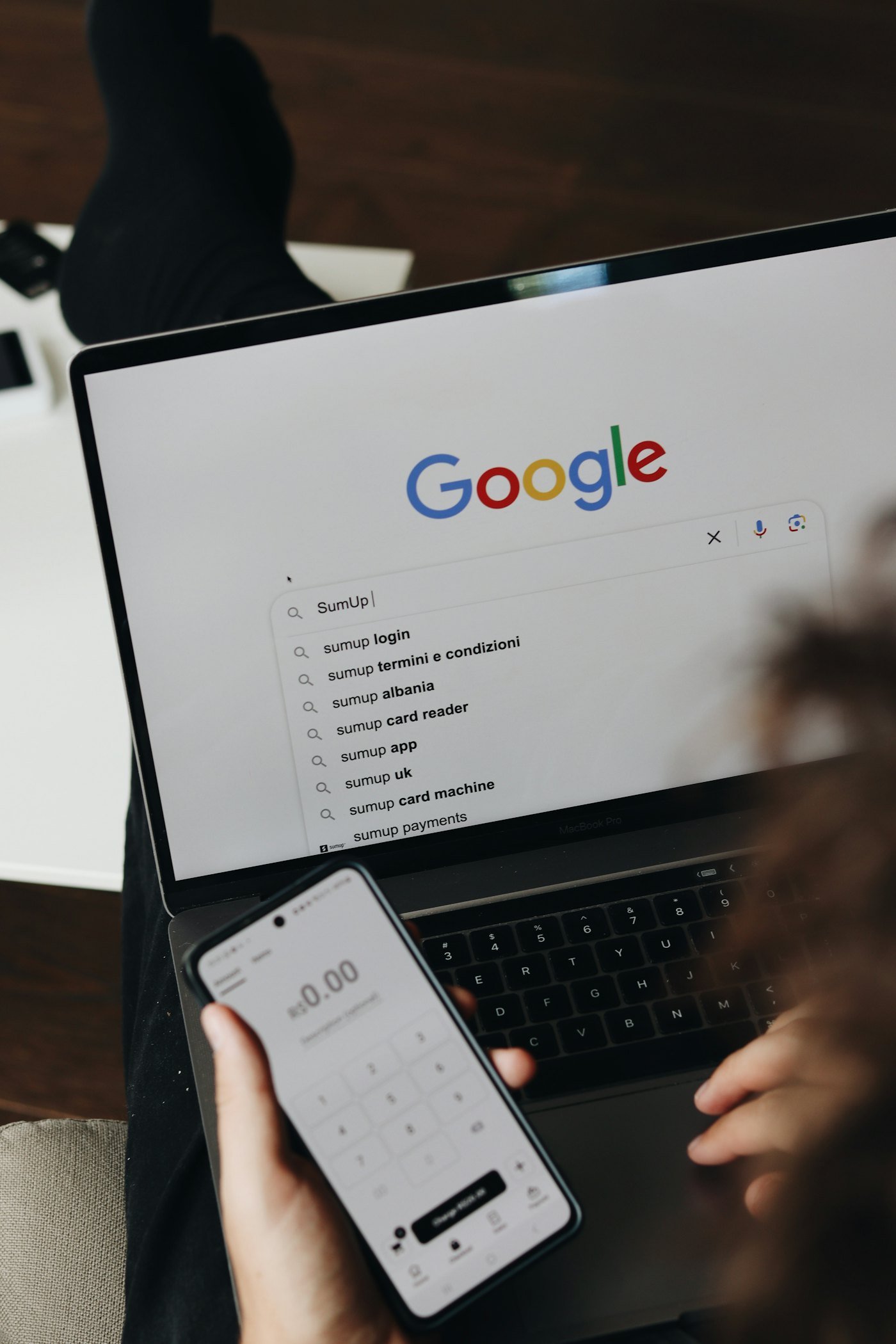 Person using a phone and laptop to search online
